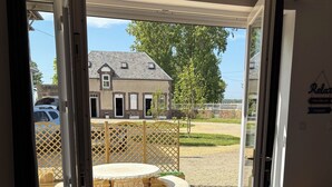 Een kamer met een tafel en stoelen, en een schuifdeur naar een terras met tuinmeubilair.
