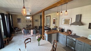 Een gezellige keuken met houten kastjes, een eethoek met een ronde tafel en hanglampen.