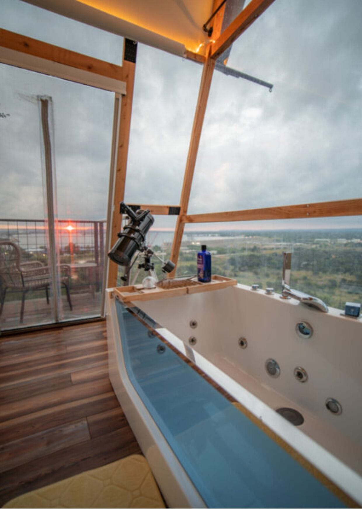 Une chambre dotée d’une grande baignoire, d’un plancher en bois et offrant une vue sur le paysage.