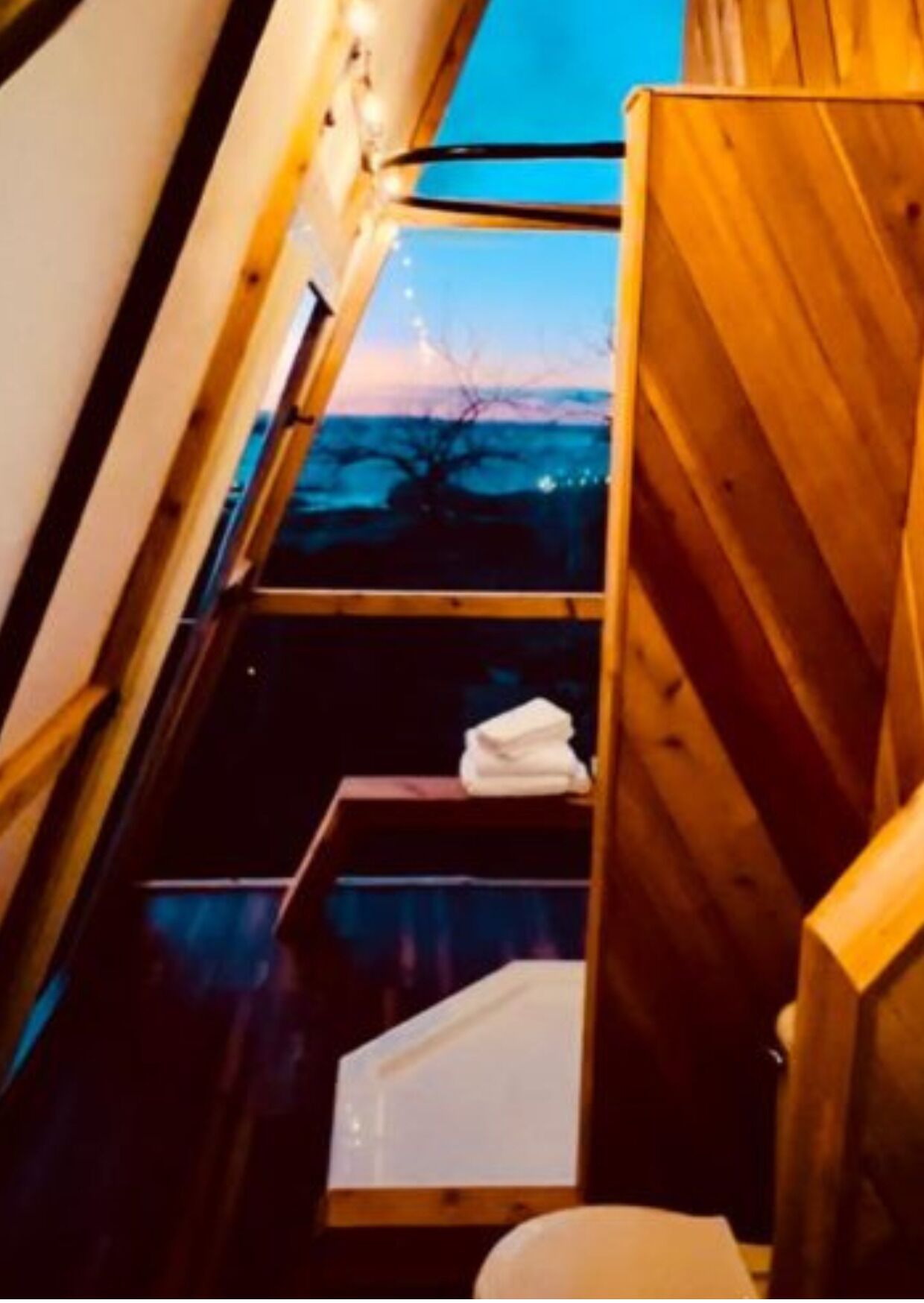 A wooden interior with a window, a white sink, and a towel on a shelf.