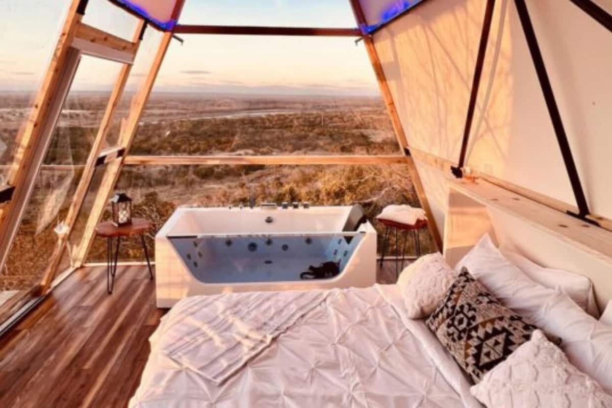 Un hébergement sous tente comprenant un lit, une baignoire et une vue sur le paysage.