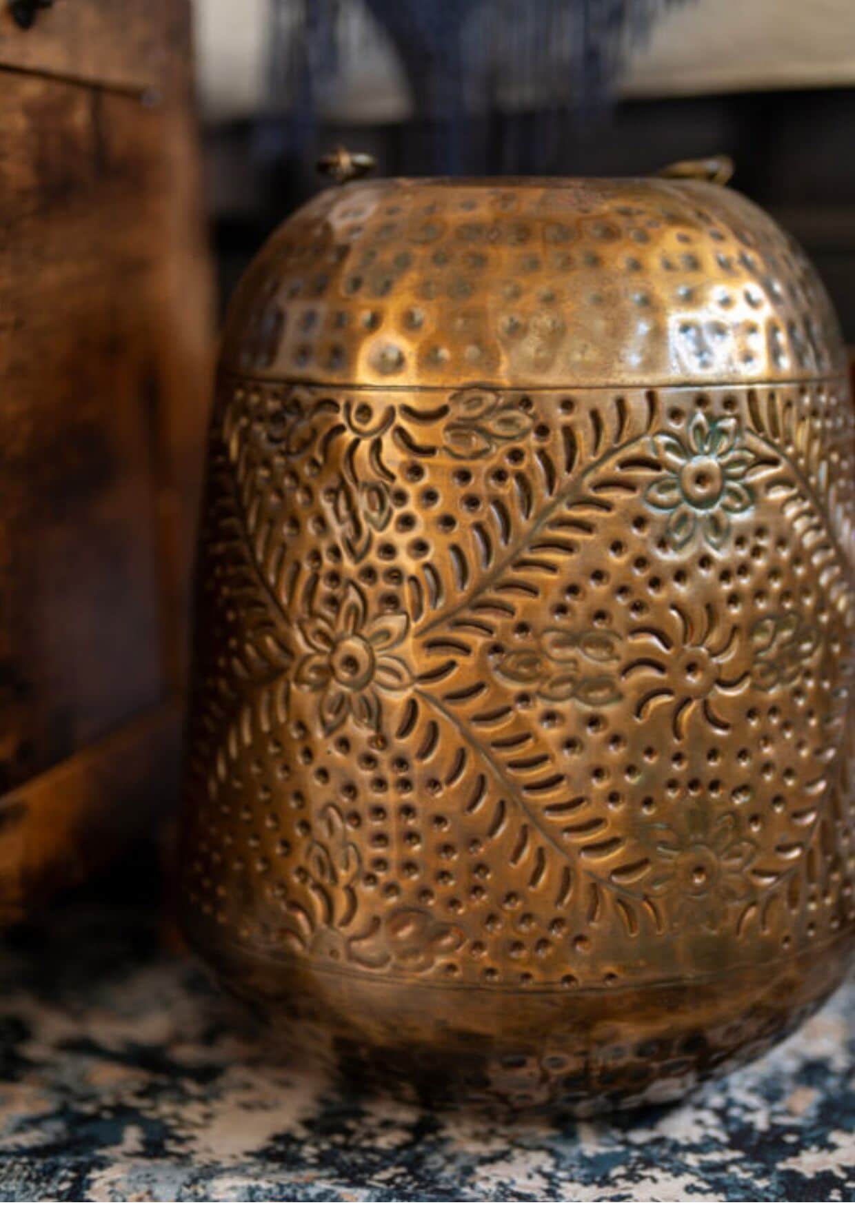 A brass decorative object with intricate floral patterns.