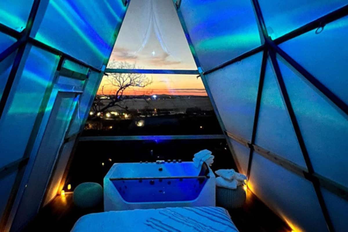 Un hébergement en tente comprenant un lit, une baignoire et une vue sur le coucher de soleil.