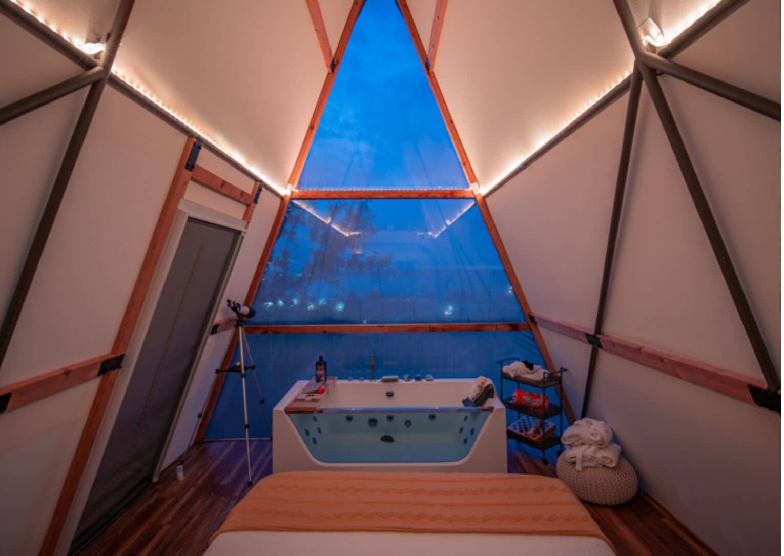 Een tent met een bed, een badkuip en een telescoop.