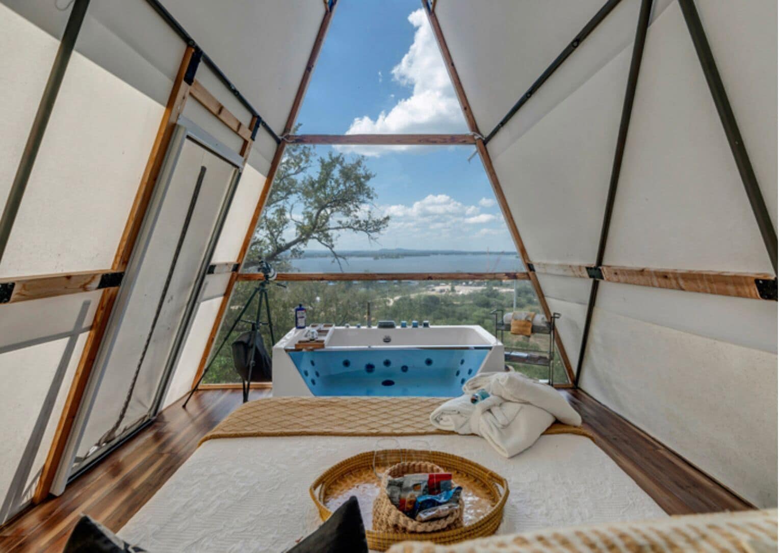 A tent with a blue bathtub, a wicker basket, and a view of the landscape.