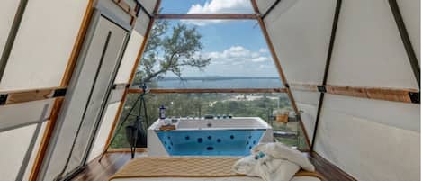 A tent with a blue bathtub, a wicker basket, and a view of the landscape.