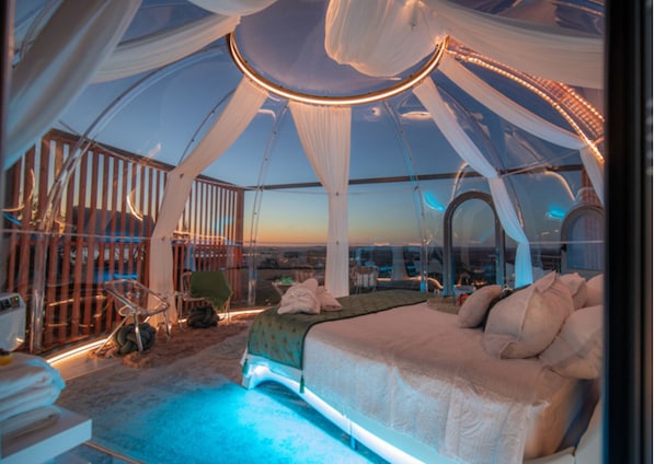 Une structure en forme de tente, comprenant un lit, une chaise et une petite table.