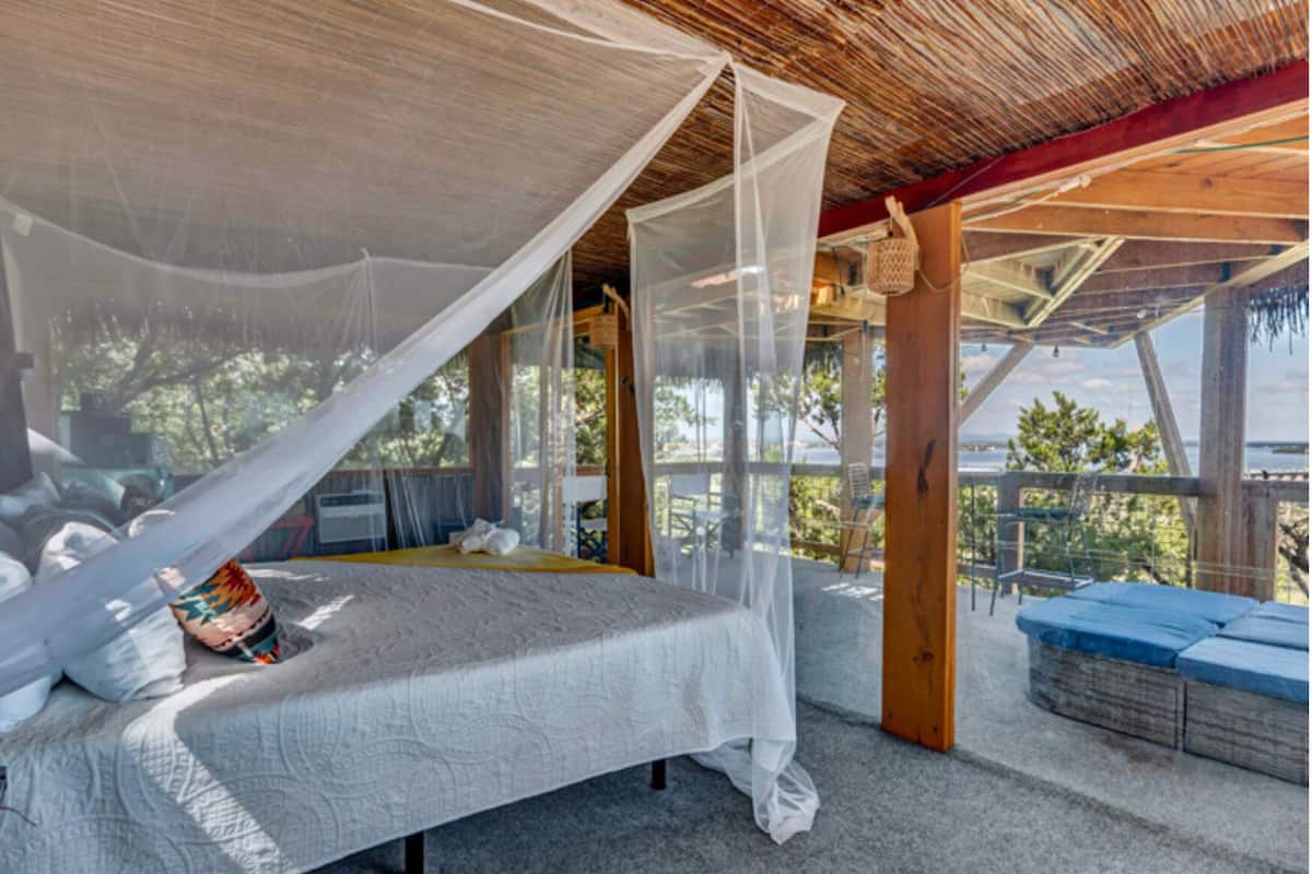 Un lit à baldaquin, une vue sur l’extérieur et un coin salon.