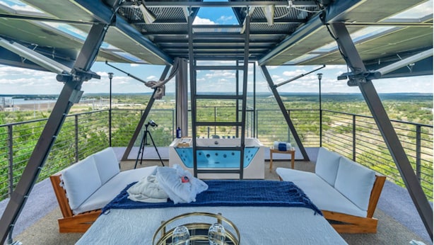 Una stanza con soffitto alto, un letto, un tavolino con dei bicchieri e vista sul paesaggio.