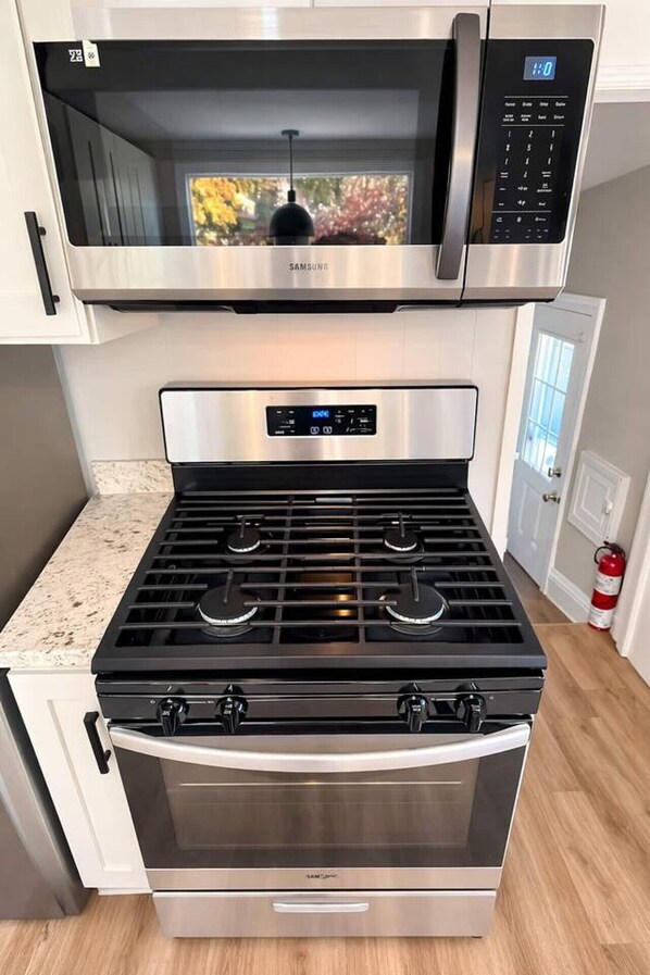 Una cocina con una campana extractora de acero inoxidable, un microondas y una estufa.