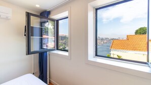 Ein Schlafzimmer mit großem Fenster, einem Bett und einer Wand-Klimaanlage.