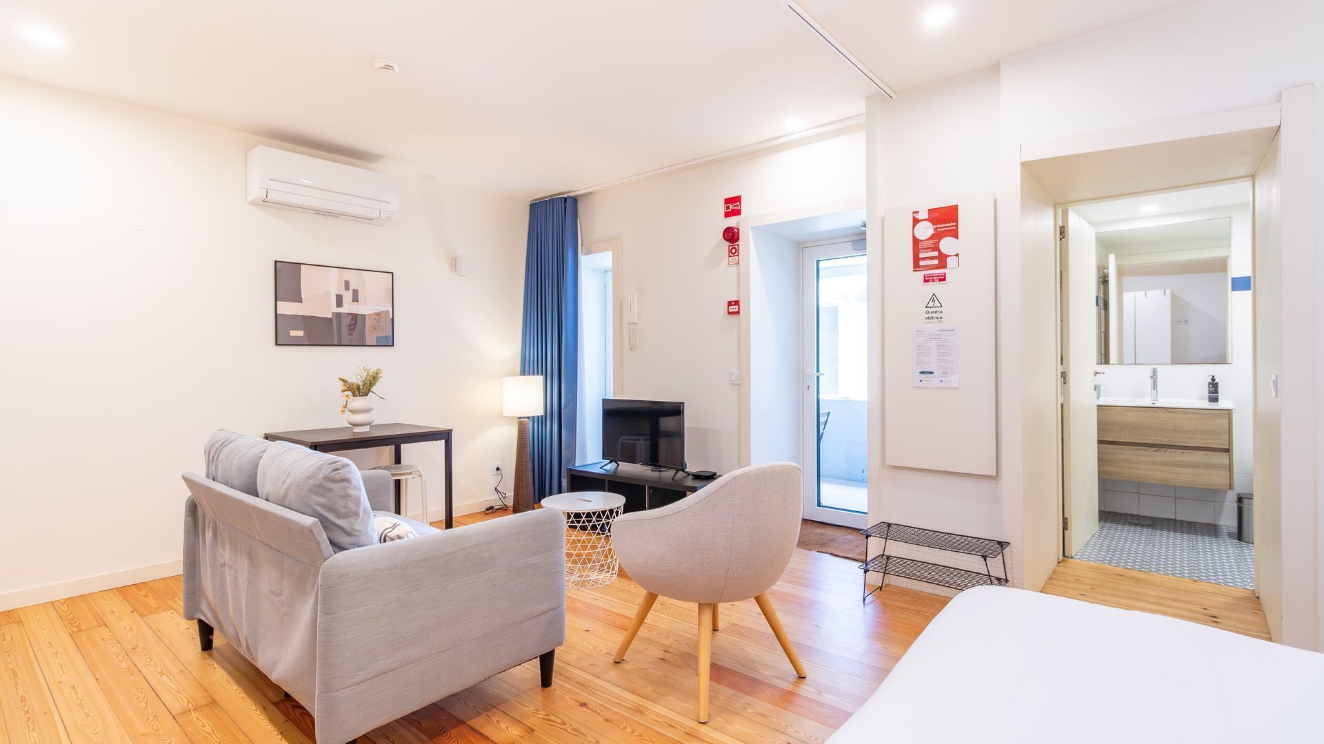 Une chambre d’hôtel moderne équipée d’un canapé, d’un fauteuil, d’une télévision et d’un lit.