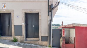 A building with two black doors, a small red structure, and a clear sky. - C: Douro & Bridge Views | Boutique Apartments (Vila Nova de Gaia)