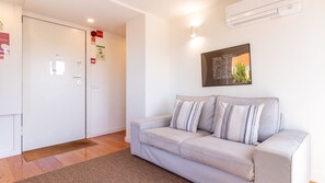 A modern living room with a sofa, a door, and an air conditioning unit. - D: Sunset Douro & Ponte Luis I Views (Vila Nova de Gaia)