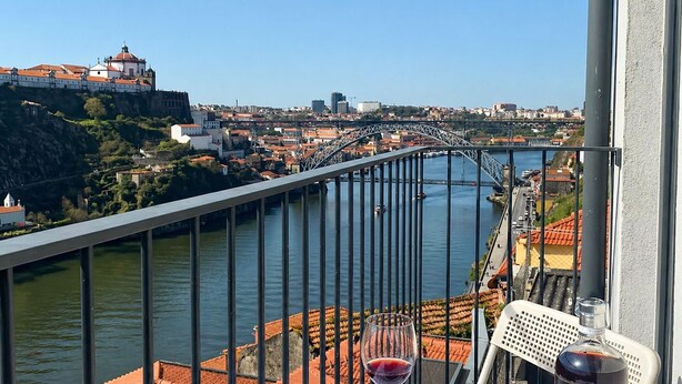 Ein Balkon mit Blick auf einen Fluss, eine Brücke und ein historisches Gebäude.