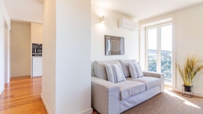 Ein modernes Apartment mit einem grauen Sofa, einem gerahmten Kunstwerk und Blick ins Freie.