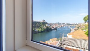 Aussicht auf einen Fluss mit einer Brücke, Gebäuden und Grünflächen.