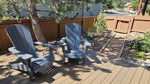 A deck with two Adirondack chairs, a wooden fence, and a garden area with rocks and plants. - Spacious 3 Bedroom Mtn Home with Private Hot Tub (Silverthorne)