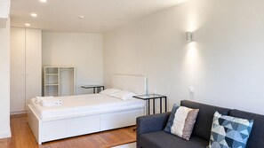 A modern hotel room with a bed, bedside tables, a sofa, and a wardrobe. - E: Sweeping Panoramic Terrace | Douro Views (Vila Nova de Gaia)