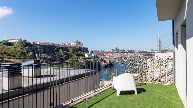 A balcony with a view of a cityscape, including buildings and a hill. - E: Sweeping Panoramic Terrace | Douro Views (Vila Nova de Gaia)