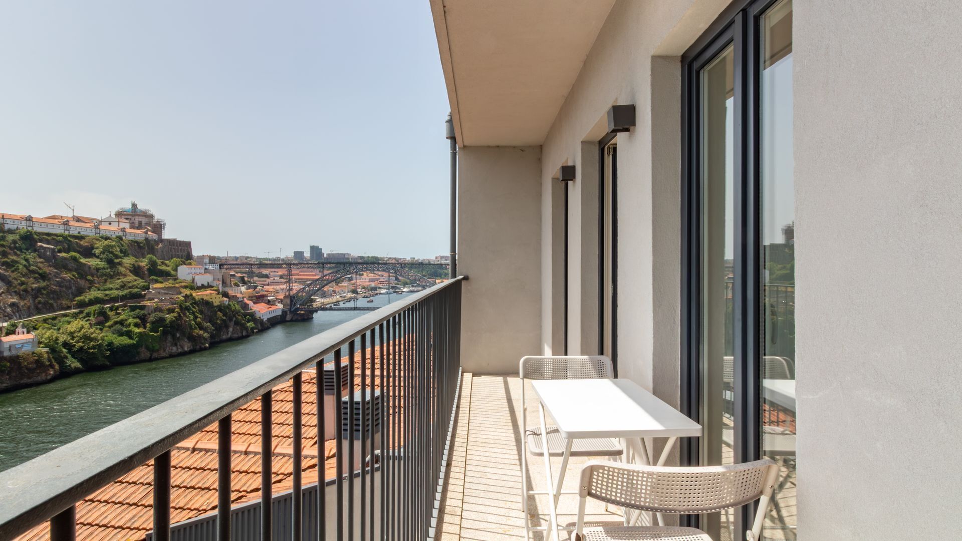 Ein Balkon mit Tisch und Stühlen mit Blick auf einen Fluss und die Skyline der Stadt.