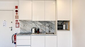 A modern kitchen with white cabinets, a marble backsplash, a coffee maker, and a microwave. - F: Ponte Luis Balcony | Riverside Flat (Vila Nova de Gaia)