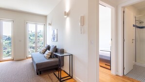 A modern living room with a sofa, a small table, and a glass shower door. - F: Ponte Luis Balcony | Riverside Flat (Vila Nova de Gaia)