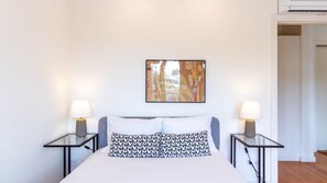 A hotel room with a bed, two bedside tables with lamps, a wall-mounted artwork, and a door leading to another room. - F: Ponte Luis Balcony | Riverside Flat (Vila Nova de Gaia)