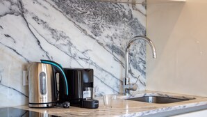 A kitchen with a marble backsplash, a coffee maker, a kettle, a glass, and a modern faucet. - F: Ponte Luis Balcony | Riverside Flat (Vila Nova de Gaia)