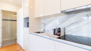 A modern kitchen with a marble backsplash, stainless steel appliances, and a built-in microwave. - G: Iconic Bridge View Balcony | Spacious 1BR Porto (Vila Nova de Gaia)