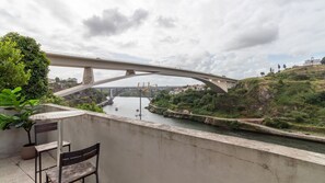 A bridge over a river with a bench and potted plant in the foreground. - G: Iconic Bridge View Balcony | Spacious 1BR Porto (Vila Nova de Gaia)