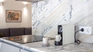 A modern kitchen with a marble countertop, a coffee machine, and a power outlet. - H: Douro & Bridge Views | Boutique Apartments (Vila Nova de Gaia)
