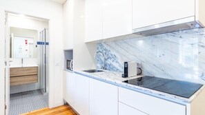 A modern kitchen with a marble backsplash, stainless steel appliances, and a wooden floor. - J: Iconic Bridge & Douro Views | 1BR Porto (Vila Nova de Gaia)