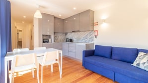 Un apartamento moderno con comedor, cocina equipada con microondas y sofá azul.