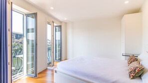 A bedroom with a bed, a balcony with glass doors, and a view of the city. - N: Secret Garden & Douro Views | Peaceful Porto (Vila Nova de Gaia)