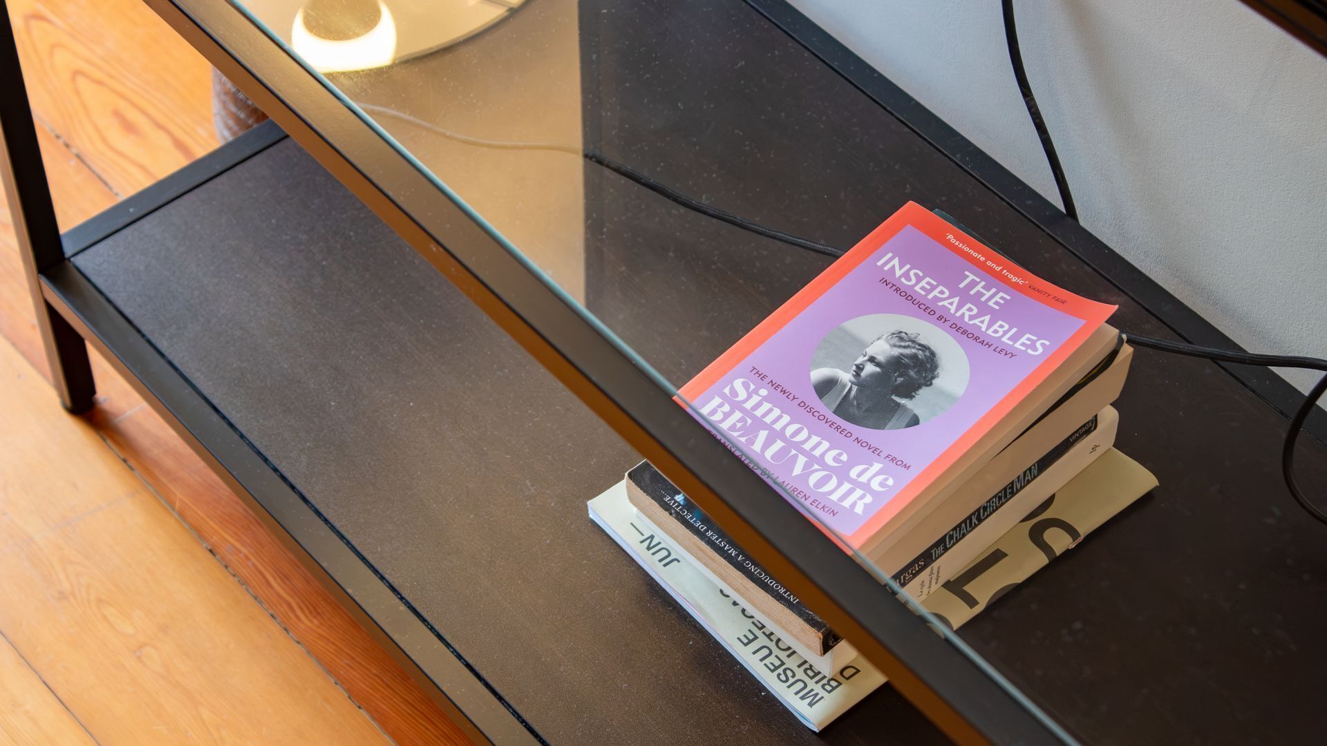 A glass-top table with a book titled 'The Inseparables' and a pen on it.