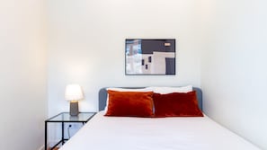 A hotel room with a bed, a nightstand with a lamp, and a wall-mounted abstract painting. - O: Douro & Bridge Views | Boutique Apartments (Vila Nova de Gaia)