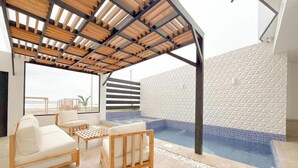 A covered outdoor seating area with a pool, wooden furniture, and a view of the beach. - Beach Front entire Private Building 32+ PAX (Montanita)