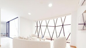 A modern living room with a white sofa, a coffee table, and a geometric wall design. - Beach Front entire Private Building 32+ PAX (Montanita)