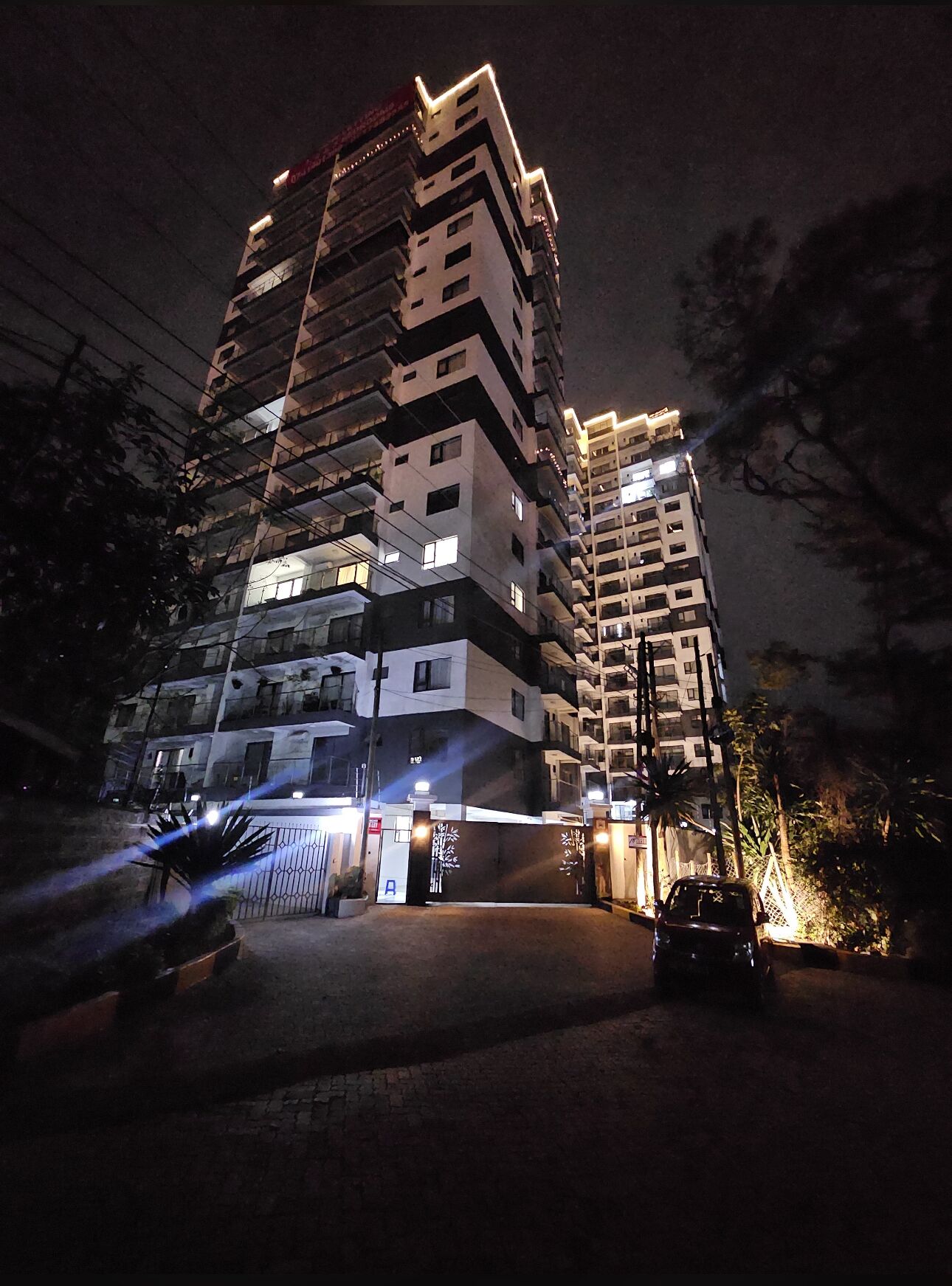 A multi-story building with a gated entrance and a parked car.