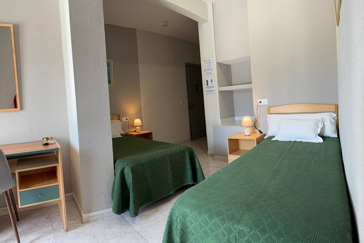 A hotel room with two beds, a desk, and a chair.