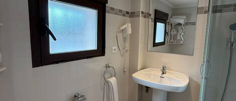 Un baño con inodoro, lavamanos, ducha y ventana.