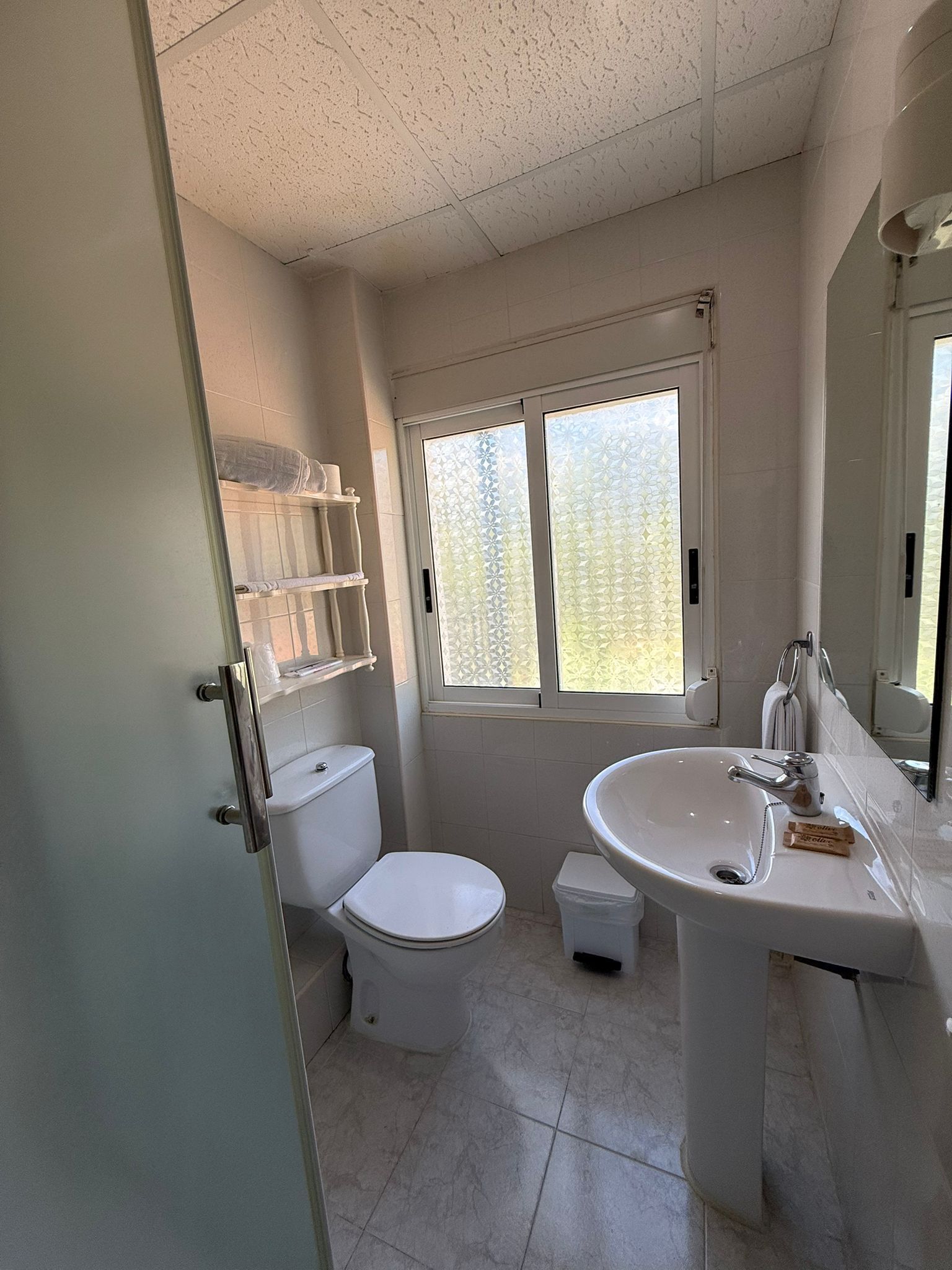 A bathroom with a toilet, sink, and window.