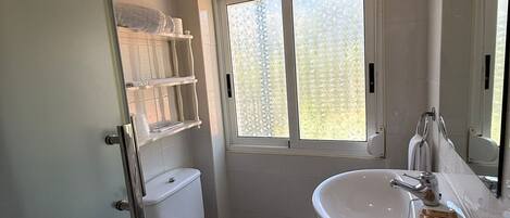 Un baño con inodoro, lavamanos y ventana.