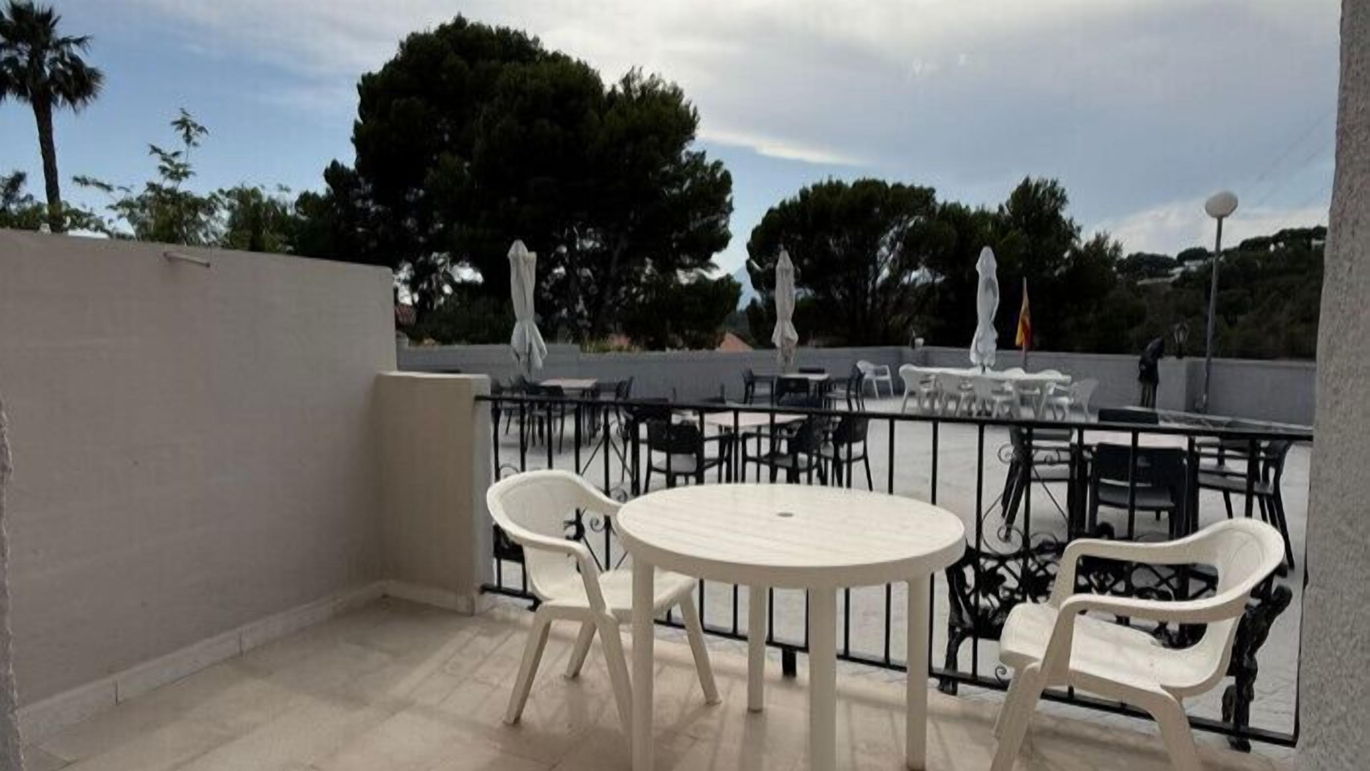 Un espace extérieur aménagé avec des tables et des chaises rondes, une rambarde et des parasols.