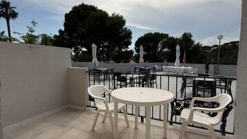 A patio area with round tables and chairs, a railing, and umbrellas.