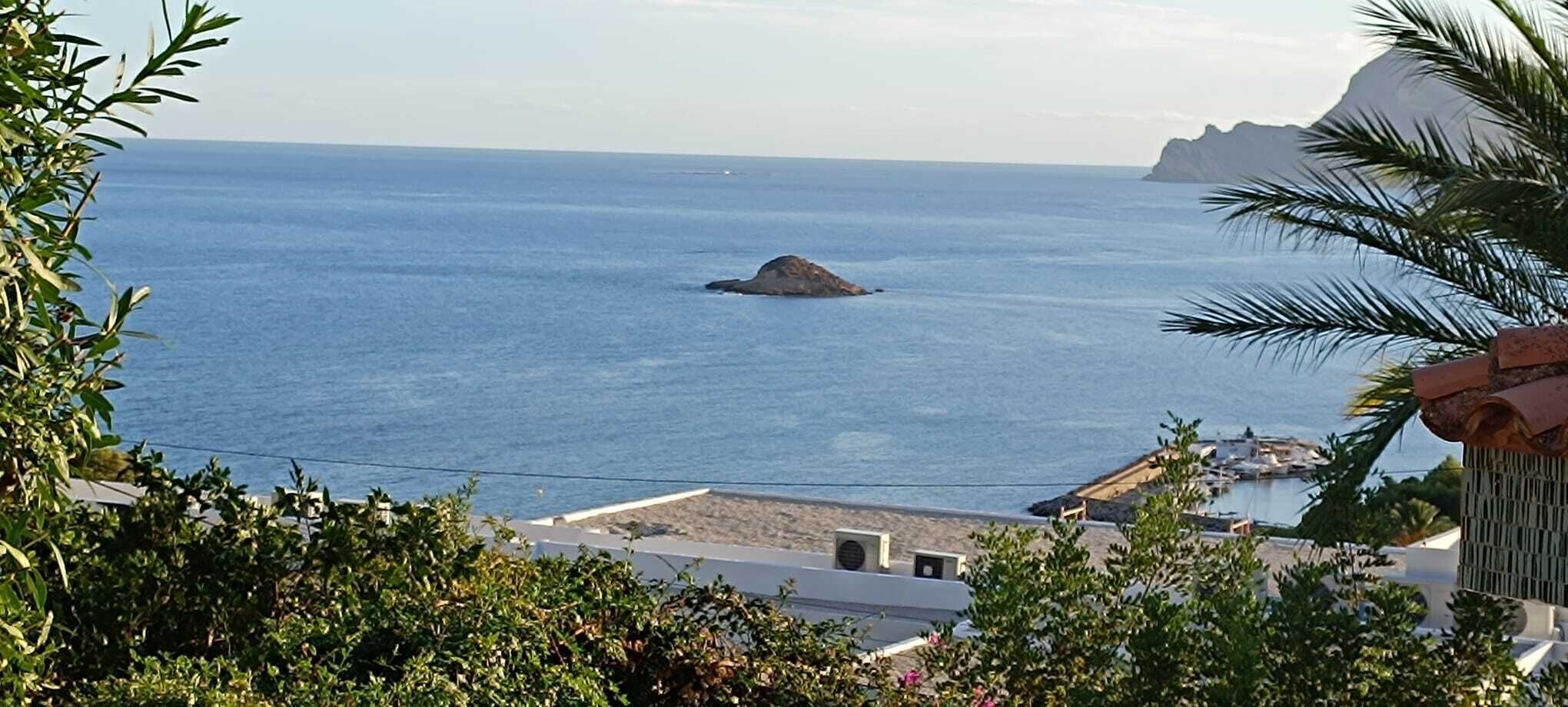 A coastal view with a small island, buildings, and vegetation.