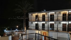 Un edificio de varios pisos con balcones, mobiliario exterior y una palmera.