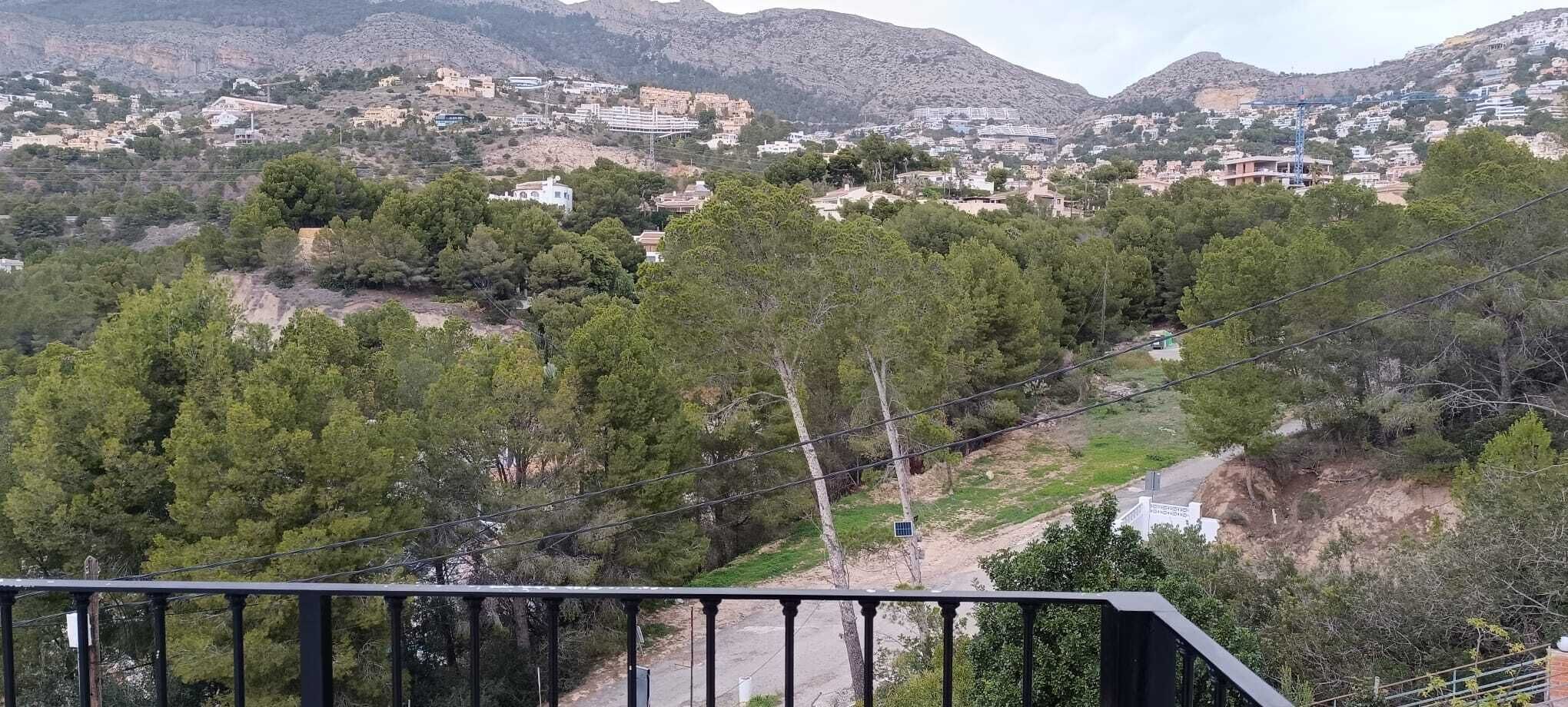 Un paysage montagneux avec des bâtiments, des arbres et un ciel dégagé.