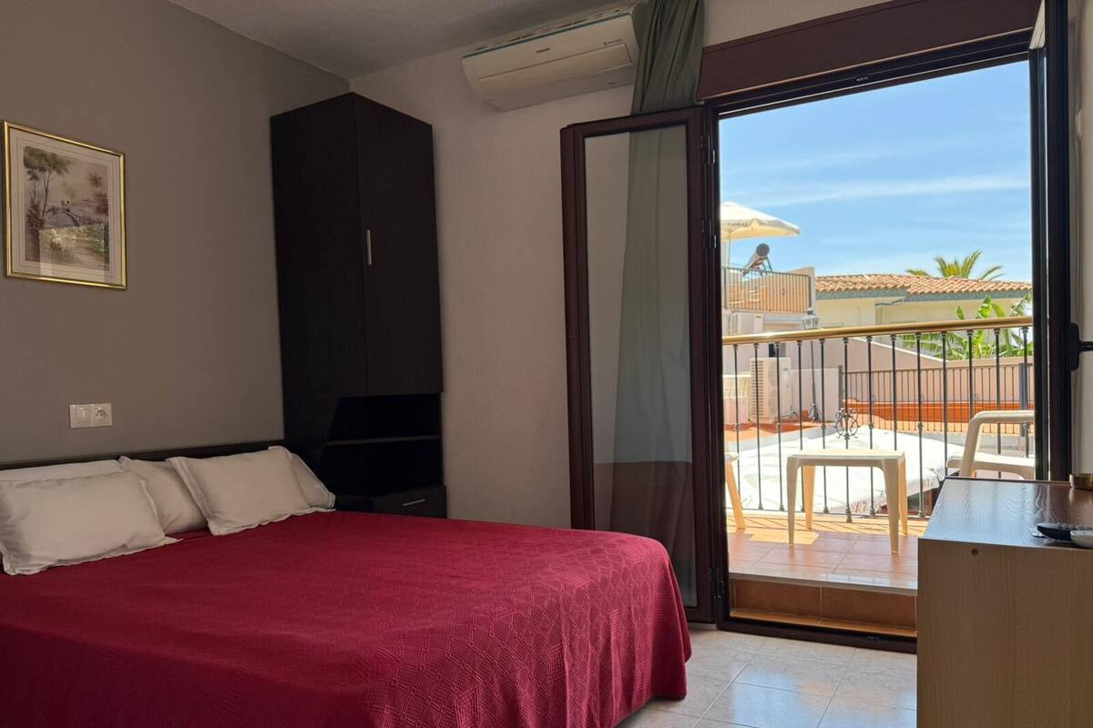 A bedroom with a bed, a wardrobe, a TV, and a balcony with a view.